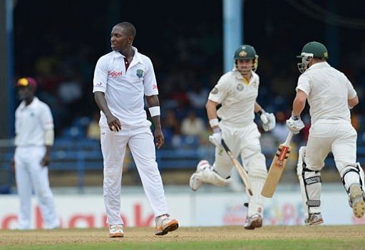 West Indies bowler Fidel Edwards (L) reacts to a shot as David Warner (R) and Ed Cowan (C) of Australia run the bases
