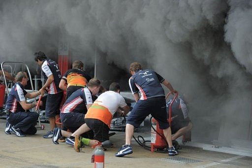 Racing team crews try to extinguish a fire in the Williams racing pit at the Circuit de Catalunya Racing team crews try to extinguish a fire in the Williams racing pit at the Circuit de Catalunya