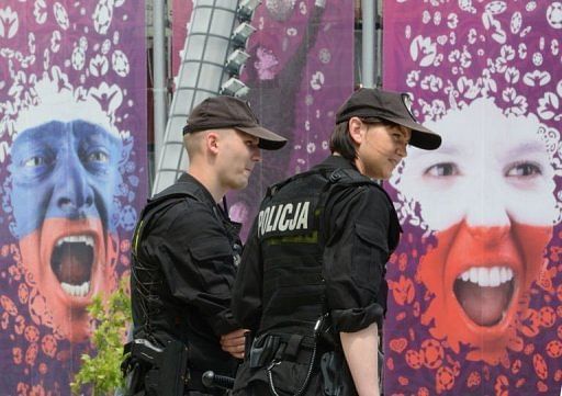 Police officers walk past a poster of a Russian (left) and Polish (right) fan at the National Stadium in Warsaw Police officers walk past a poster of a Russian (left) and Polish (right) fan at the National Stadium in Warsaw