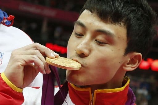 Gold medalist China's gymnast Feng Zhe celebrates on the podium of the men's parallel bars