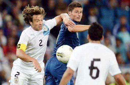 French forward Olivier Giroud (C) clashes with Uruguayan defender Diego Lugano (L) French forward Olivier Giroud (C) clashes with Uruguayan defender Diego Lugano (L)
