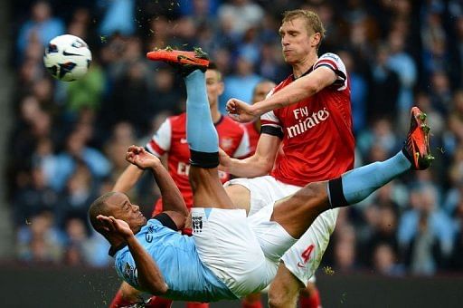 Manchester City's Vincent Kompany (L) attempts an overhead kick as Arsenal's Per Mertesacker stands clear Manchester City's Vincent Kompany (L) attempts an overhead kick as Arsenal's Per Mertesacker stands clear