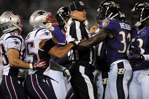 A referee seperates players from the New England Patriots and the Baltimore Ravens A referee seperates players from the New England Patriots and the Baltimore Ravens