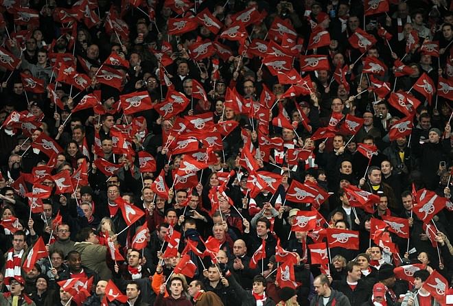 Arsenal fans wave flags before barcelona team flag. Arsenal fans wave flags before